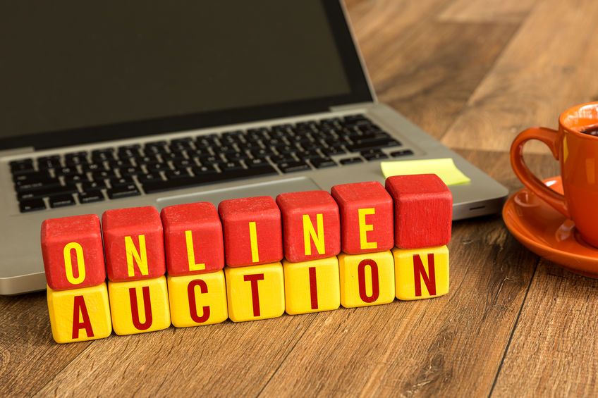 Träklossar med texten ONLINE AUCTION framför en laptop och kaffekopp.