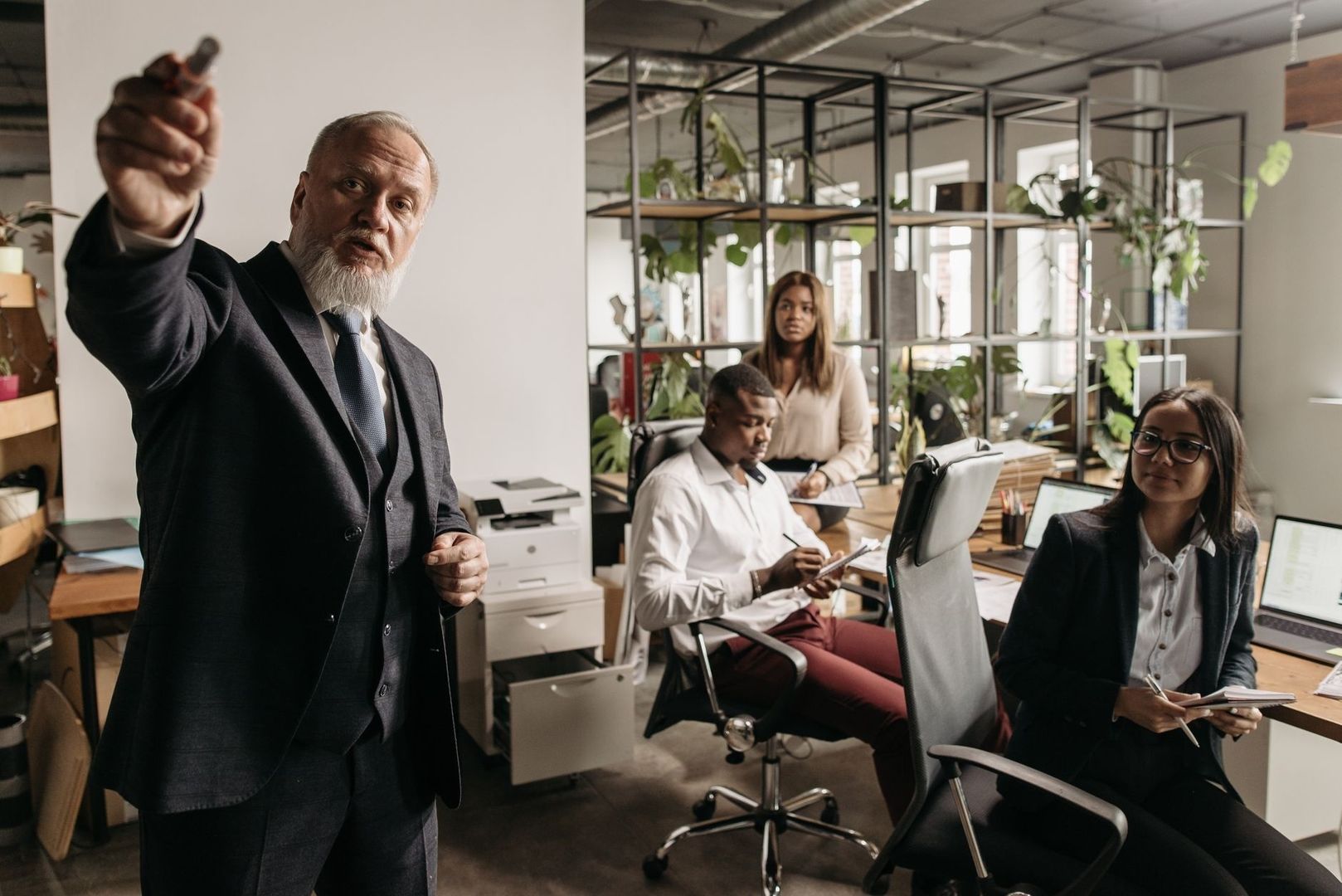 Chef i kostym instruerar sitt team på ett ljust kontor